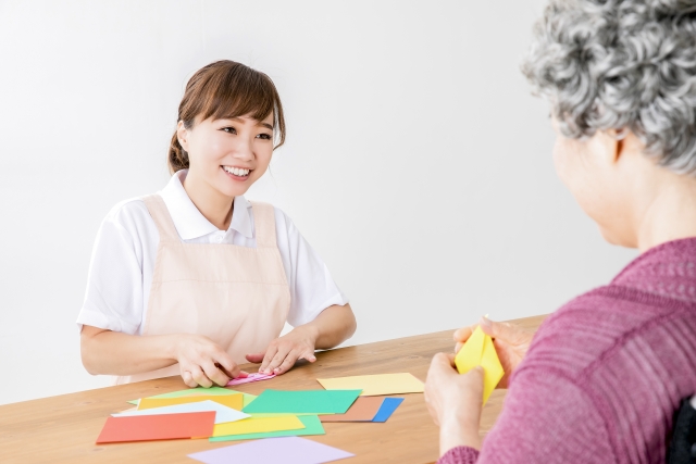 介護士が高齢者とカードゲームを楽しむ様子