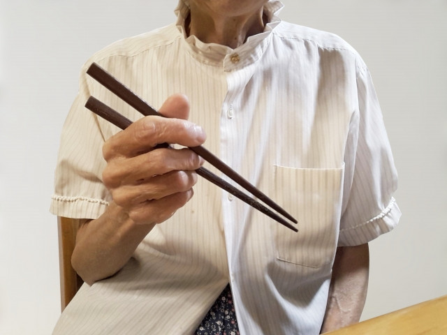 高齢者が箸を使って食事をする様子